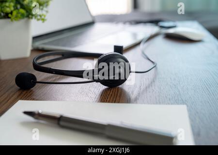 Kopfhörer, die für ein Online-Meeting mit einem Laptop verbunden sind, werden während der Pause beiseite gelegt. Stockfoto