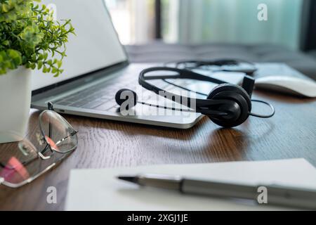 Kopfhörer, die für ein Online-Meeting mit einem Laptop verbunden sind, werden während der Pause beiseite gelegt. Stockfoto