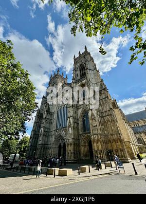 Weite Sicht auf die Vorderseite des York Minster unter einem blauen bewölkten Himmel. Stockfoto