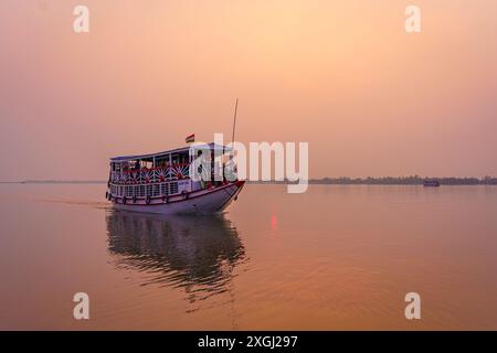 Sundarbans, Indien - 20. Oktober 2023: Ein traditionelles Touristenboot segelt bei Sonnenuntergang auf einem Wasserkanal. Konzept des Safaritourismus im Sundarb Stockfoto