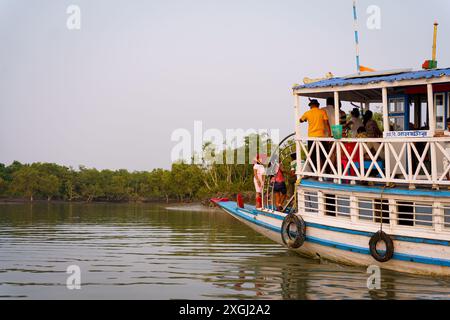 Sundarbans, Indien - 20. Oktober 2023: Ein traditionelles Touristenboot segelt bei Sonnenuntergang auf einem Wasserkanal. Konzept des Safaritourismus im Sundarb Stockfoto