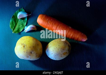 Frische Zutaten: Karotten in Scheiben, geschälte Kartoffeln, Lorbeerblatt und Knoblauch Stockfoto