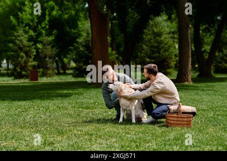 Ein glückliches Schwulenpaar spielt mit ihrem labrador Retriever in einem grasbewachsenen Park, umgeben von Bäumen. Stockfoto