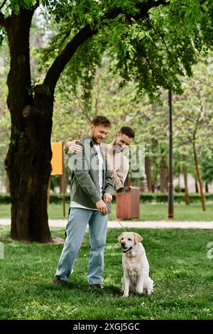 Ein bärtiges Schwulenpaar in lässiger Kleidung spaziert mit seinem labrador in einem grünen Park. Stockfoto