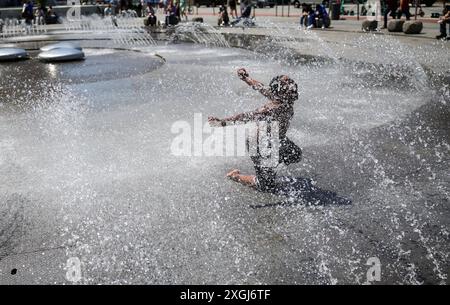 München, Deutschland. Juli 2024. Ein Junge erfrischt sich bei Sommertemperaturen im Wasserspiel Stachus im Zentrum Münchens. Quelle: Christian Charisius/dpa/Alamy Live News Stockfoto