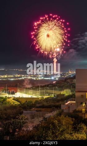 Ein platzendes Feuerwerk erleuchtet den Nachthimmel über einer Stadtlandschaft und schafft eine farbenfrohe und festliche Atmosphäre. Bei Langzeitbelichtung erfasst. Stockfoto