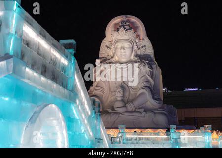 1. Januar 2022, HARBIN, CHINA. Vertikales Bild spektakulärer beleuchteter weißer Eisskulpturen in Harbin, China. Nachtbild mit Kopierraum für Tex Stockfoto