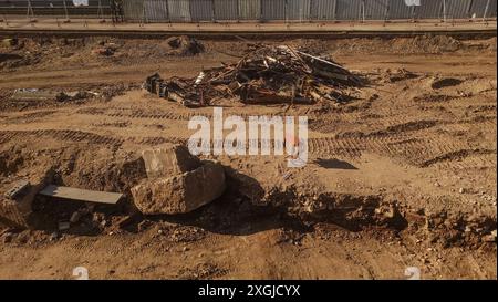 Ein großer Felsen befindet sich auf einer unbefestigten Baustelle mit Schutt und Reifenspuren Stockfoto