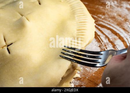 Torte machen: Oberste Kruste. Schließen Sie den Kreis, der mit einer Gabel versiegelt wird, indem Sie die Kanten zusammendrücken. Stockfoto