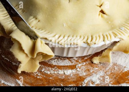 Torte machen: Oberste Kruste. Überschüssiger Teig wird mit einem Messer vom Kuchen abgeschnitten. Stockfoto