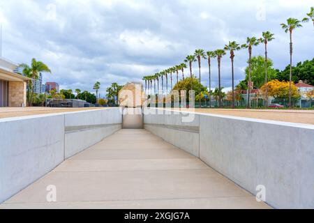 Los Angeles, Kalifornien - 4. April 2024: LACMA's berühmter Felsbrocken in der Mitte des Betonweges, eingerahmt von Palmen, unter bewölktem Himmel. Stockfoto