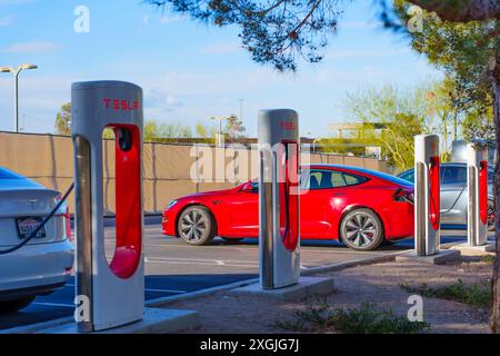 Los Angeles, Kalifornien - 15. April 2024: Das rote Tesla Elektrofahrzeug lädt an der Tesla Supercharger Station auf dem Parkplatz mit anderen Autos, umgeben Stockfoto