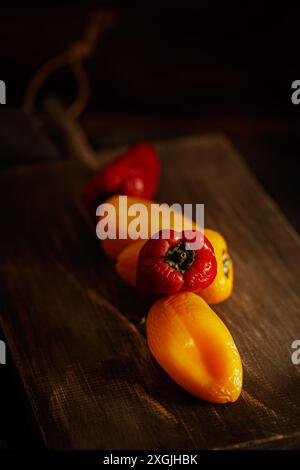 Ein Haufen Paprika ist auf einem hölzernen Schneidebrett. Die Paprika sind rot und gelb. Die Anordnung der Paprika schafft ein Gefühl von Balance und Harmonie Stockfoto