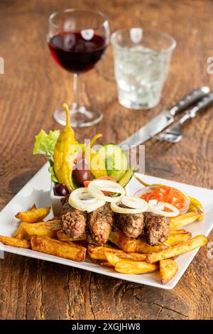 Cevapcici mit pommes frites und Zwiebelringen Stockfoto