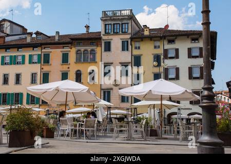 Udine, Italien - 9. Juli 2024. Eine kleine Gruppe von Teenagern unterhält sich während einer Hitzewelle unter einem Barschirm auf der Piazza Giacomo Matteotti Stockfoto