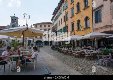 Udine, Italien - 9. Juli 2024. Eine kleine Gruppe von Teenagern unterhält sich unter einem Barschirm, während eine Hitzewelle im Zentrum von Udine beginnt Stockfoto