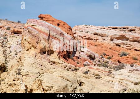 Ein felsiger Hügel mit einem großen Felsen in der Mitte. Der Fels ist eine Mischung aus roten, gelben und braunen Farben Stockfoto