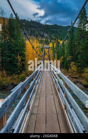 Hölzerne Hängebrücke über einen Fluss in einem bunten Herbstwald Stockfoto