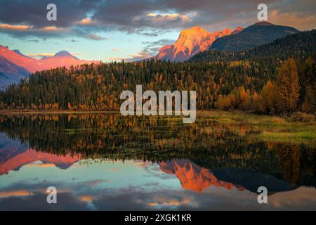 Dramatischer Sonnenaufgang, der Berggipfel beleuchtet, die sich an einem wunderschönen Herbsttag in einem ruhigen See spiegeln Stockfoto