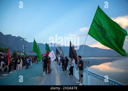 Srinagar, Indien. Juli 2024. Kaschmiri-schiitische Muslime halten islamische Fahnen, die an der Uferstraße in Srinagar angebracht werden. Muharram ist der erste Monat des islamischen Kalenders. Es ist einer der heiligsten Monate im islamischen Kalender. Schiitische Muslime gedenken Muharram als einen Monat der Trauer zum Gedenken an das Martyrium des islamischen Propheten Muhammads Enkel Imam Hussain, der 680 n. Chr. auf Ashura (10. Tag Muharram) in der Schlacht von Karbala getötet wurde Stockfoto