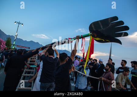 Srinagar, Indien. Juli 2024. Kaschmiri-schiitische Muslime halten eine islamische Flagge, die an der Uferstraße in Srinagar angebracht wird. Muharram ist der erste Monat des islamischen Kalenders. Es ist einer der heiligsten Monate im islamischen Kalender. Schiitische Muslime gedenken Muharram als einen Monat der Trauer zum Gedenken an das Martyrium des islamischen Propheten Muhammads Enkel Imam Hussain, der 680 n. Chr. auf Ashura (10. Tag Muharram) in der Schlacht von Karbala getötet wurde Stockfoto