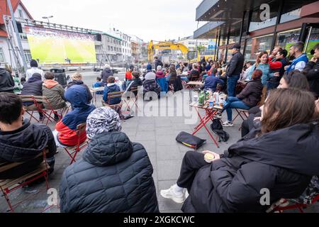 Fußballfans verfolgen anlässlich der Fußball-Europameisterschaft UEFA EURO 2024 das Halblfinalspiel Spanien gegen Frankreich auf einer Leinwand auf dem Platz Hlemmur in Rsykajvik. / Fußballfans sehen das Halbfinalspiel zwischen Spanien und Frankreich auf einem Bildschirm auf dem Hlemmur-Platz in Rsykajvik während der UEFA EURO 2024 Fußball-Europameisterschaft. UEFA Fußball-Europameisterschaft - Fußballfans *** Fußballfans sehen das Halbfinalspiel zwischen Spanien und Frankreich auf einem Bildschirm auf dem Hlemmur-Platz in Rsykajvik während der UEFA EURO 2024 Fußball-Europameisterschaft der UEFA so Stockfoto