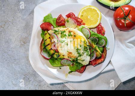 Luxuriöses Sandwich mit gegrillter Avocado, Spiegelei, Tomaten, Rettich, Salat auf geröstetem Brot zum Frühstück, Mittag- oder Abendessen, Blick von oben Stockfoto