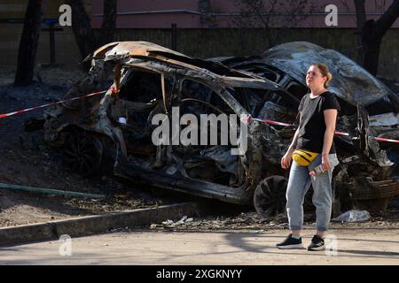 Eine Frau steht vor dem Hintergrund eines ausgebrannten Autos in der Nähe eines fünfstöckigen Wohnhauses im Bezirk Holosiivskyi, das durch einen russischen Raketenangriff in Kiew zerstört wurde. Am Morgen führte die russische Armee einen Raketenangriff auf die ukrainischen Städte Kiew, Dnipro, Kryvyi Rih, Slowiansk, Kramatorsk, mit mehr als 40 Raketen verschiedener Art. In Kiew wurden Wohngebäude, Infrastrukturanlagen und das Kinderkrankenhaus „Okhmatdyt“ beschädigt. Retter suchen weiterhin nach Menschen unter den Trümmern. (Foto: Aleksandr Gusev/SOPA Images/SIPA USA) Stockfoto