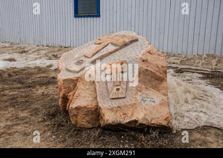 Steinschnitzereien von maskierten Gesichtern auf einem Felsen im Inuit Sculpture Park bei den Four Corners in Iqaluit, Nunavut, Kanada Stockfoto