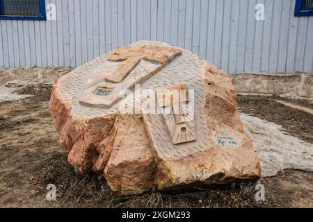 Steinschnitzereien von maskierten Gesichtern auf einem Felsen im Inuit Sculpture Park bei den Four Corners in Iqaluit, Nunavut, Kanada Stockfoto