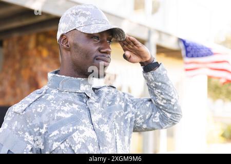 Lächelnder afroamerikanischer Soldat in Uniform und Mütze, der draußen grüßt. Militärdienst, Armee, Arbeit, Aufmerksamkeit und Pflicht, unverändert. Stockfoto