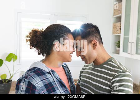 Schwules, birassisches Paar teilt einen zärtlichen Moment zu Hause. Sie zeigen Zuneigung und Nähe in einer gemütlichen, häuslichen Umgebung. Stockfoto