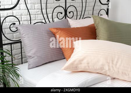 Gestreifte Kissen auf einem Bett mit Kopfteil aus schwarzem Metall Stockfoto