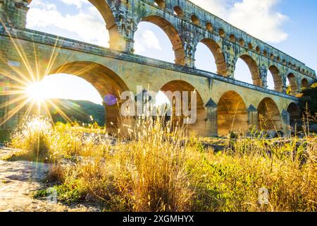 Der prächtige Pont du Gard, der von der untergehenden Sonne beleuchtet wird. Antike römische dreistufige Aquäduktbrücke, die im 1. Jahrhundert n. Chr. erbaut wurde, um Wasser zum zu transportieren Stockfoto