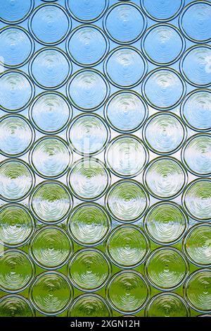 Blick durch eine undurchsichtige Glasscheibe mit grüner Wiese und blauem Himmel Stockfoto