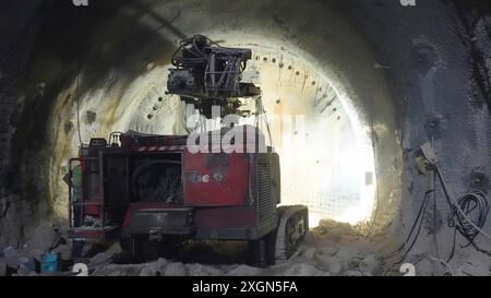 Schwere Maschinen, die in einem schwach beleuchteten Tunnel im Bau betrieben werden Stockfoto