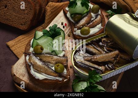 Sandwiches, Schwarzbrot mit Sprotten, Frischkäse, Gurken, auf einem Schneidebrett, Blick von oben, Nahaufnahme, keine Leute Stockfoto