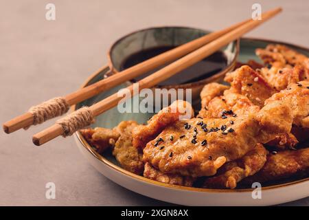 Frittiertes Fleisch im Teig, frittiert, mit Sesamsamen und Sojasauce, auf einem grauen Tisch, es gibt keine Leute Stockfoto