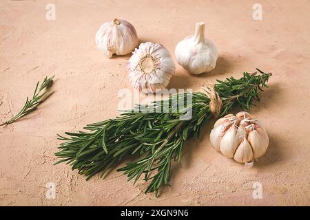 Frischer Rosmarin mit Knoblauch, auf beigefarbenem Hintergrund, Lebensmittelkonzept Stockfoto