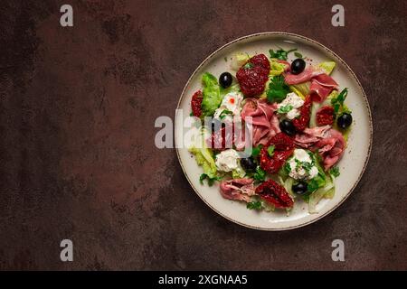 Salat mit getrockneten Tomaten, Schinken, Frischkäse, Oliven, hausgemacht, Draufsicht Stockfoto