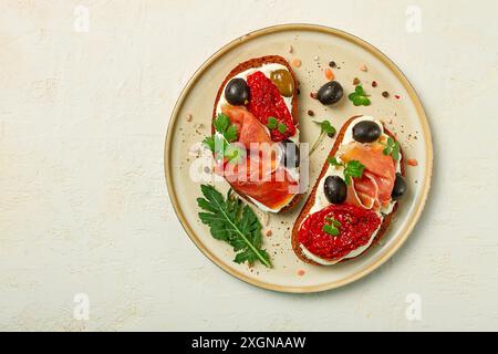 Sandwiches mit Käse und Schinken, getrockneten Tomaten und Oliven, Frühstück auf einem Teller Stockfoto