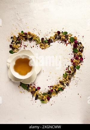 Tee-Set, Herzform, mit einer Tasse, Draufsicht, auf weißem Hintergrund, Rosenknospen, Jasmin, Blau, Chrysantheme, Minzblätter Stockfoto