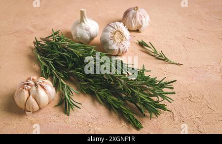 Frischer Rosmarin mit Knoblauch, auf beigefarbenem Hintergrund, Lebensmittelkonzept Stockfoto