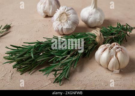 Frischer Rosmarin mit Knoblauch, auf beigefarbenem Hintergrund, Lebensmittelkonzept Stockfoto