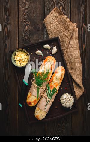 Baguette mit Knoblauchbutter und Kräutern, gebraten, auf einem braunen Holztisch, Blick von oben, rustikaler Stil, keine Leute Stockfoto