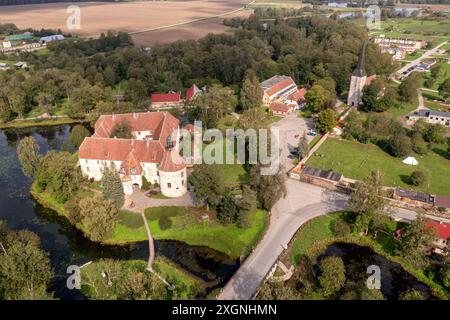 Ein großes Schloss, umgeben von Wasser und Bäumen, steht an einem sonnigen Tag. Stockfoto
