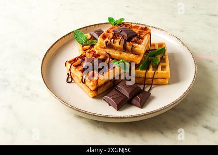 Wiener Waffeln, mit Schokolade, Frühstück, auf beigefarbenem Hintergrund, keine Leute, selektiver Fokus, Waffeln, Dessert, Schokolade, Minze Stockfoto