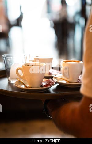 Nahaufnahme eines Tabletts mit Kaffee, der von einem Kellner beim Frühstück gehalten wird. Vertikal Stockfoto