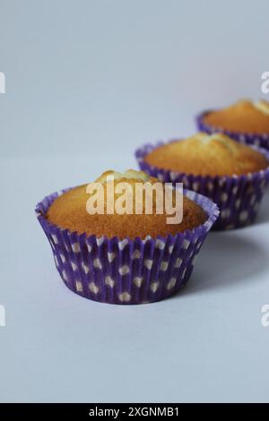 Drei Muffins in lila Tupfen auf weißem Hintergrund Stockfoto