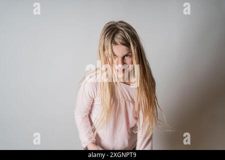 Ein junges Mädchen tanzt gerne mit und ohne rosa Bluse. Ihr langes, blondes Haar schwebt durch die Luft: Lebenslust: Temperament, Bewegung, Toben, Stockfoto